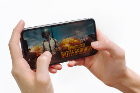 Samara Russia - 04.05.2020: Hands holding a smartphone Iphone 11 with PUBG mobile game on display screen, Illustrative Editorial. Mobile game loading screen.のeditorial素材