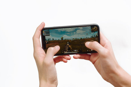 Samara Russia - 04.05.2020: Hands holding a smartphone Iphone 11 with PUBG mobile game on display screen, Illustrative Editorial.のeditorial素材