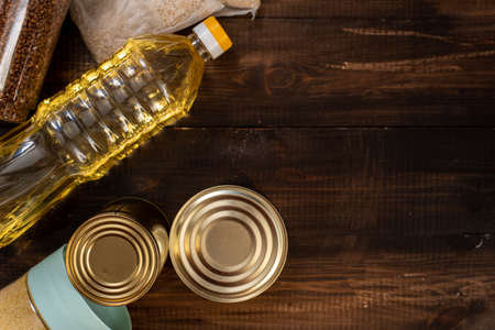 Cereals, various products, canned food, pasta and soap on a wooden background with place for text. Humanitarian assistance during the coronavirus pandemic. Stock of non-perishable foods.の写真素材