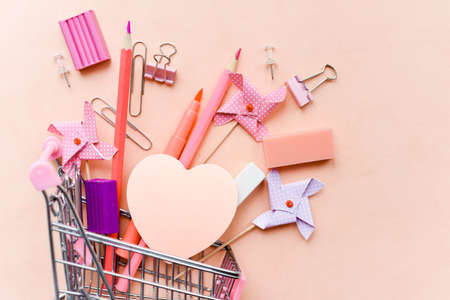 Stationery and stickers on a pink background in a shopping cart. Office supplies for school.の写真素材
