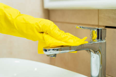Someone is washing a sink in yellow gloves. Someone is cleaning a bathroom with detergents.の写真素材