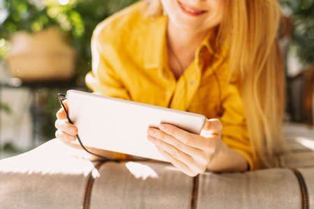 Beautiful woman communicates with family and friends using a tablet. A lovely girl is sitting in her...