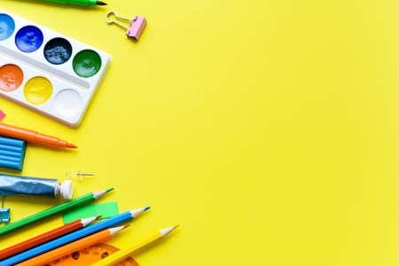 School supplies on a yellow background with place for text. Scissors, paints, pencils, children's...