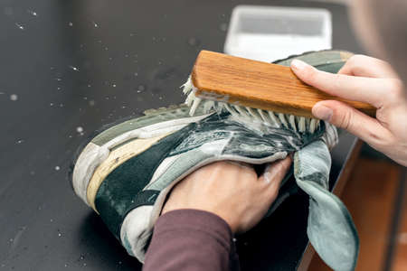Cleaning suede sneakers. A worker in a shoe workshop cleans a pile of shoes.の写真素材
