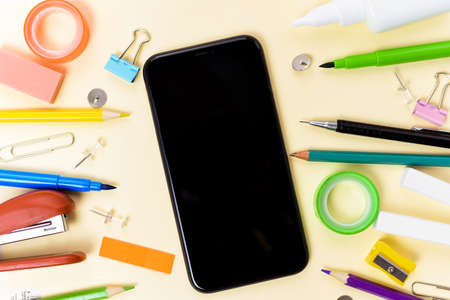Office supplies near the phone on a beige background. The concept of electronic distance learning.の写真素材