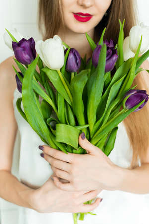 A beautiful girl is holding a big bouquet. A girl with a bouquet of tulips.の写真素材
