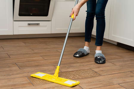 A woman washes underfloor heating in her house. A mop in the hands of a housekeeper.