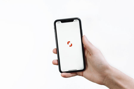 Samara Russia - 04.05.2020: A young man holds in his hand an iPhone 11 with the Shutterstock open application for contributors on a white isolated background.のeditorial素材