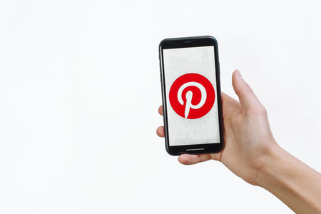Samara Russia - 04.05.2020: A man holds an iPhone 11 in his hand with the Pinterest app on a white...