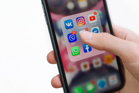 Samara Russia - 04.05.2020: A man hand holds an iPhone 11 and chooses between social networks. Communication in VK, Facebook, Telegram messengers.のeditorial素材