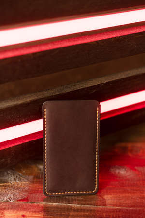 Leather phone case on a wooden background in neon light.