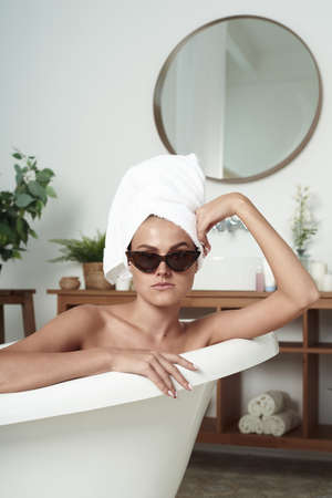 Lovely stylish girl takes a bath. Woman in a spa salon. A girl in sunglasses in a hotel.の写真素材