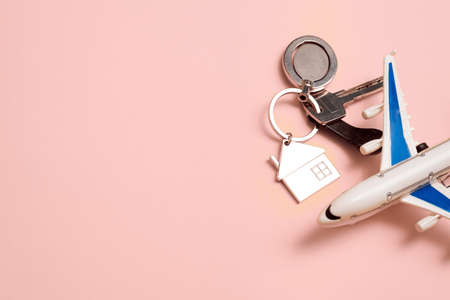 Airplane model and apartment keys with a keychain in the form of a house. Flight cancellation due to the impact of coronavirus COVID-19 concept.の写真素材