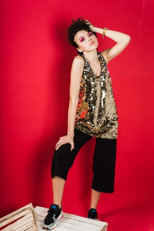 Nice, young girl with pink smoky sweaters and sneakers on a red background.の写真素材