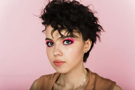 Portrait of a beautiful model with bright pink make-up and flying hair.