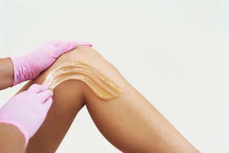 Woman is applying epilation paste. The hair removal procedure on the white background.の写真素材