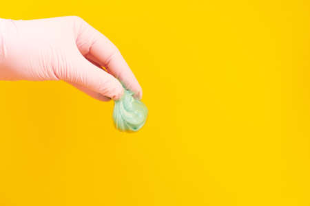 Hand is holding the epilation paste on the yellow background.