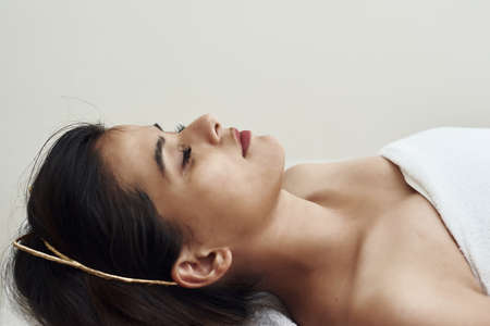 A young woman is lying on a couch by a beautician or masseur. Detached hair and bathrobe. Facial...