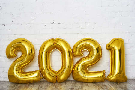 Figurine 2021 from balloons on a light brick background. New year celebration. Gold Air Balloons....
