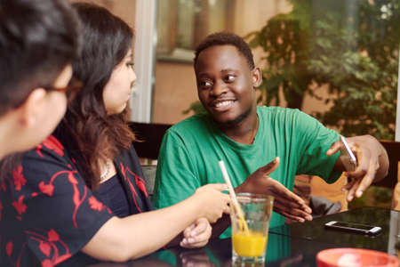 Multiracial group of friends having a coffee together. A young black man explains something to his...