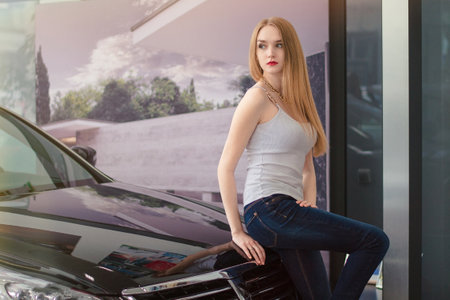 Buying new car. Smiling young woman being glad about her newly-bought car.の写真素材