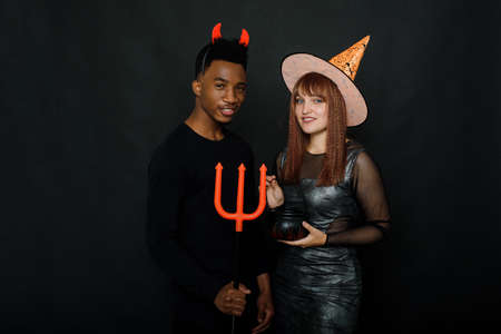 Two friends celebrate Halloween in the studio in costumes on a black background. Halloween party concept.の写真素材