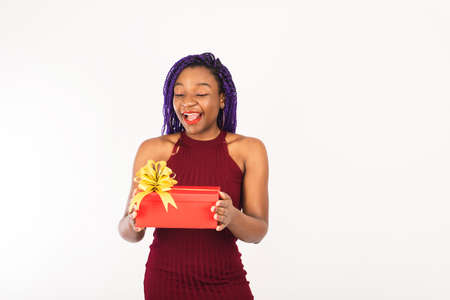 A black young woman enjoys a Christmas red big gift. Young woman smiles and receives gift. Isolated on white background.の写真素材