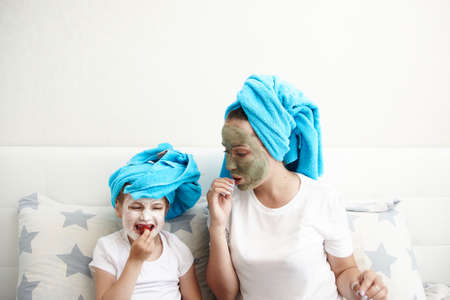 Mom with her daughter making clay face mask. Mother with child doing beauty treatment together.