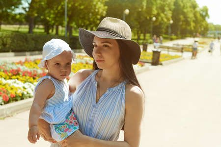 A mother and a little girl is looking into camera. Mother and daughter is in the park.