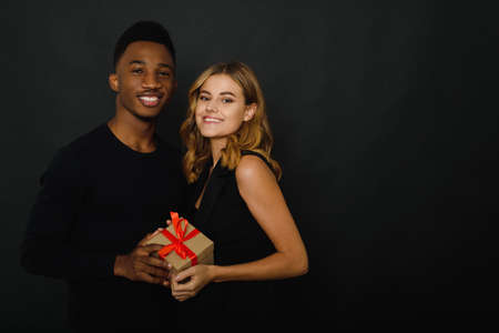 Couple of professional international models feeling good posing together with gift. Giving a gift....