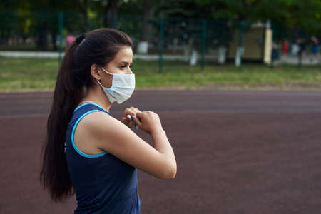 A young girl goes in for sports on the street in a protective mask. Sport during quarantine, coronavirus, covid-19 concept.の写真素材