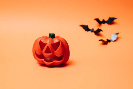 Artificial bats and pumpkin on an orange background. Happy Halloween holiday concept. Flat lay, top view, copy space.の写真素材