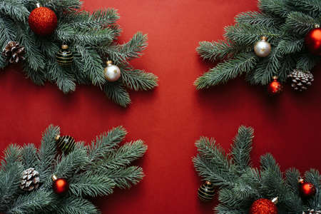 Christmas red decorations, fir tree branches on red background. Flat lay. Nature Christmas concept....