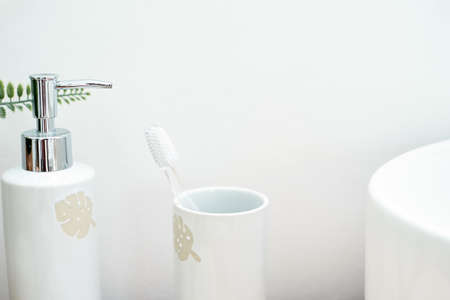Plastic toothbrush, liquid soap in the dispensary over white background near sink.の写真素材