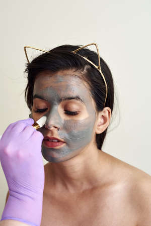 The beautician applies a moisturizing mask to the clients face.