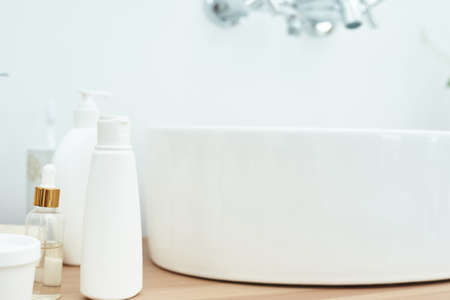 Body care cosmetics with accessories near sink in bathroom. Lotion, serum and mask on the wooden table.の写真素材