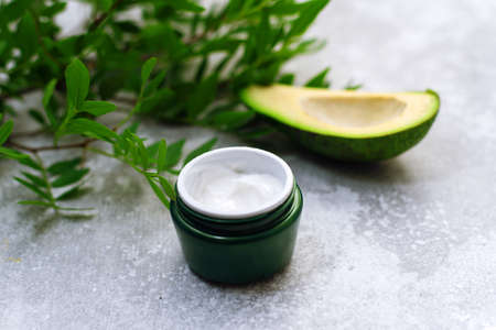 Bowl of body cream with avocado on greyの写真素材