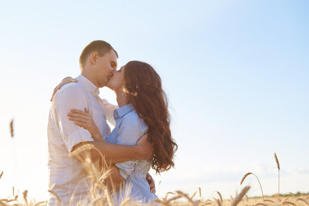Young couple hugs in the wheat field, kiss and enjoy life. The concept of love and correct non-abusive relationships.の写真素材