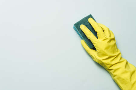 yellow rubber glove is holding sponge on the white background. yellow rubber glove is cleaning with sponge.の写真素材