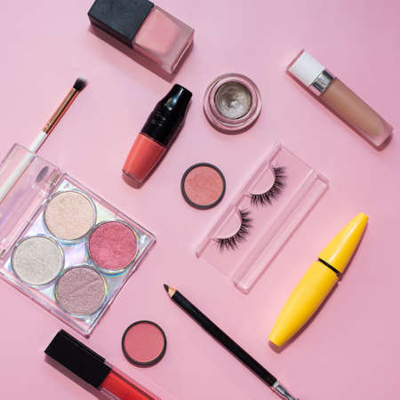 False eyelashes, brushes for applying eye shadow and powder, palette of eye shadow and lipstick on a pink background. The concept of makeup, work of a make-up artist and cosmetics.の写真素材