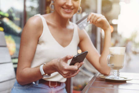 Smart phone online shopping in woman hand. Desk with coffee in background. Hands holding credit card and using mobile smart phone, Online shopping.の写真素材