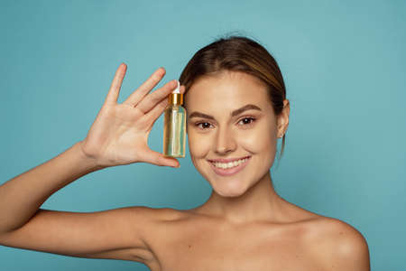 A beautiful young woman moisturizes her skin with a serum. Caring for the skin.の写真素材