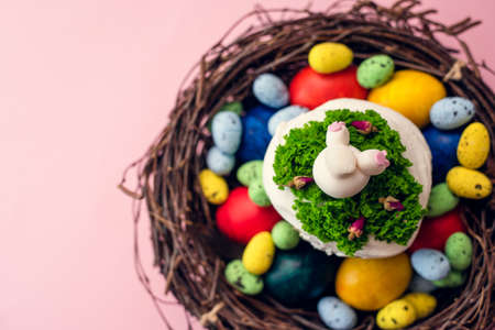 Easter cake decorated with cream in the form of grass and a rabbit butt figurine in a basket on a...