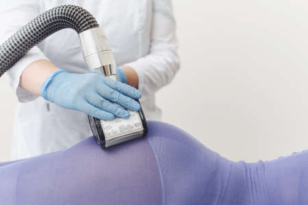Beautician makes LPG massage of the booty of a young woman in a purple suit. Lymphatic drainage massage. Slimming treatments.の写真素材