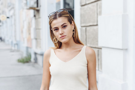 Summer sunny lifestyle fashion portrait of young stylish hipster woman walking on the street, wearing cute trendy outfit, smiling enjoy her weekends.の写真素材