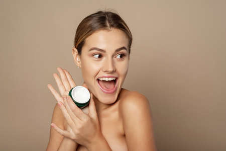 Young beautiful woman with smile holding a jar of cream. Face skin care. Beauty treatmentの写真素材