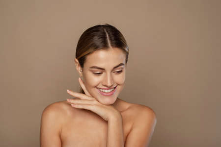 Beautiful Caucasian young woman with perfect skin touching faceの写真素材