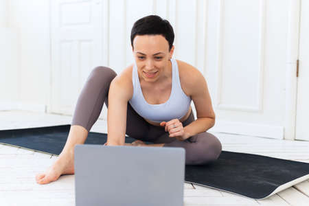 Woman with laptop computer at yoga studio. Fitness, technology and healthy lifestyle conceptの写真素材