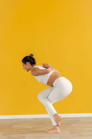 Close up of young woman joining hands behind her back while doing yoga exercise. Young attractive yogi woman practicing yoga, making Namaste behind the backの写真素材