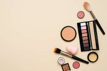 Face powder, brush and various cosmetic decorative makeup products on a color background. Close up. Makeup brush and decorative cosmetics on a pastel background with copy spaceの写真素材